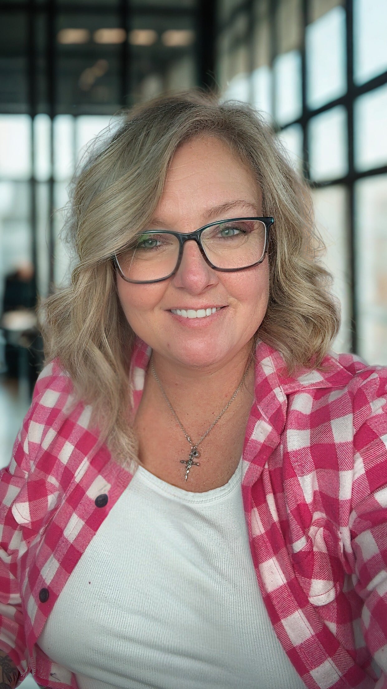 Woman wearing glasses and a pink checkered shirt indoors